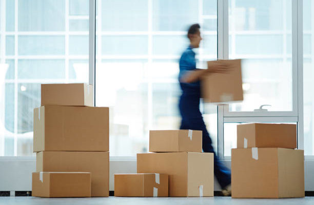 DEM BUREAUX 1 Blurred motion of contemporary worker with packed box walking to new office while delivering it to client